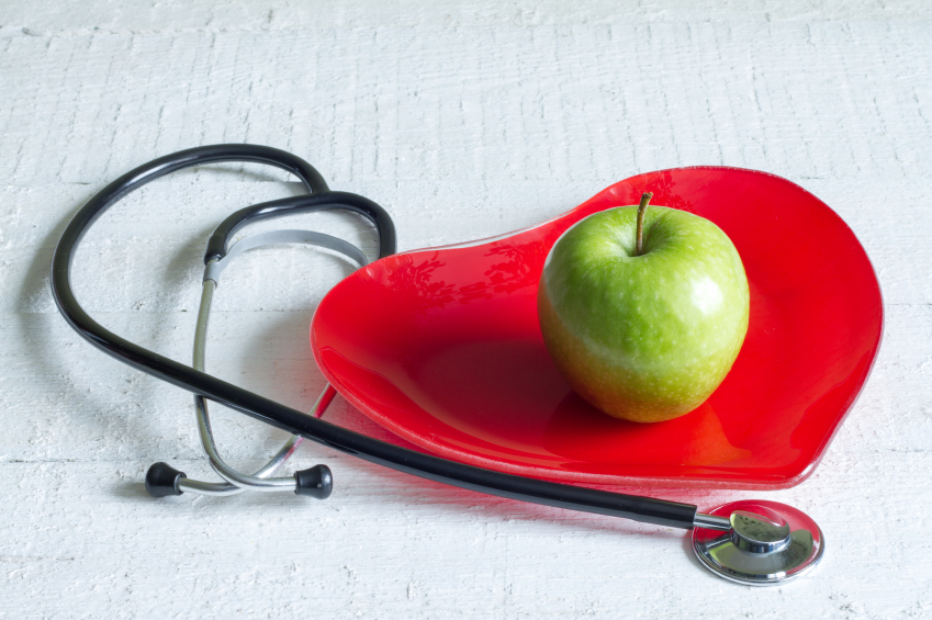 Fonendoscopio, plato rojo con forma de corazón y manzana verde encima 