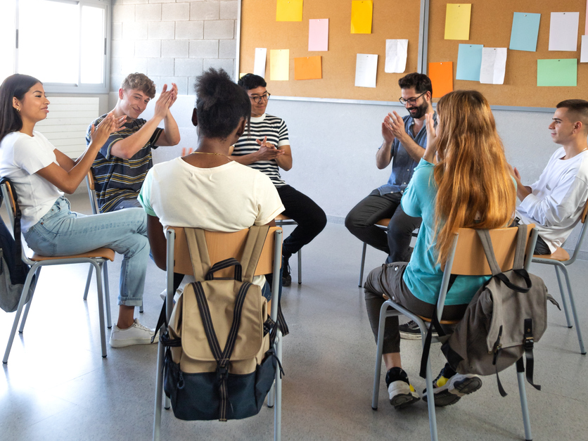 Un grup de joves seuen en cercle a una sala.