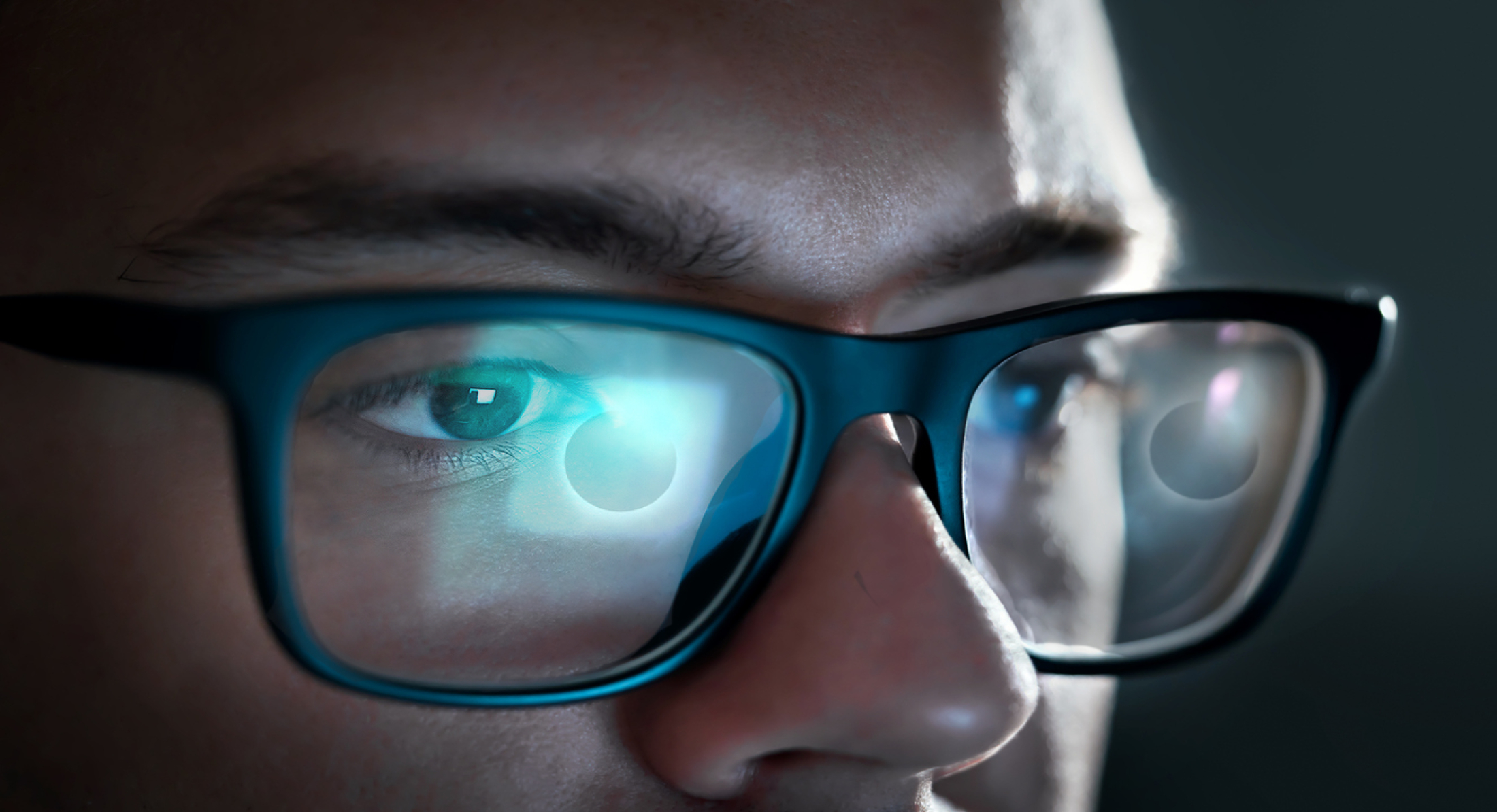 La pantalla de un ordenador con un eclipse solar se refleja en las gafas de un joven.