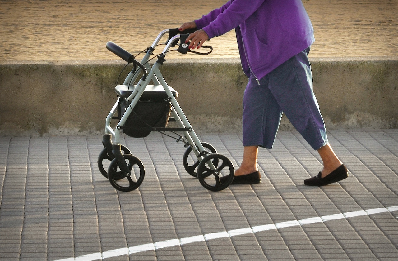 Una dona major camina amb l'ajuda d'un caminador