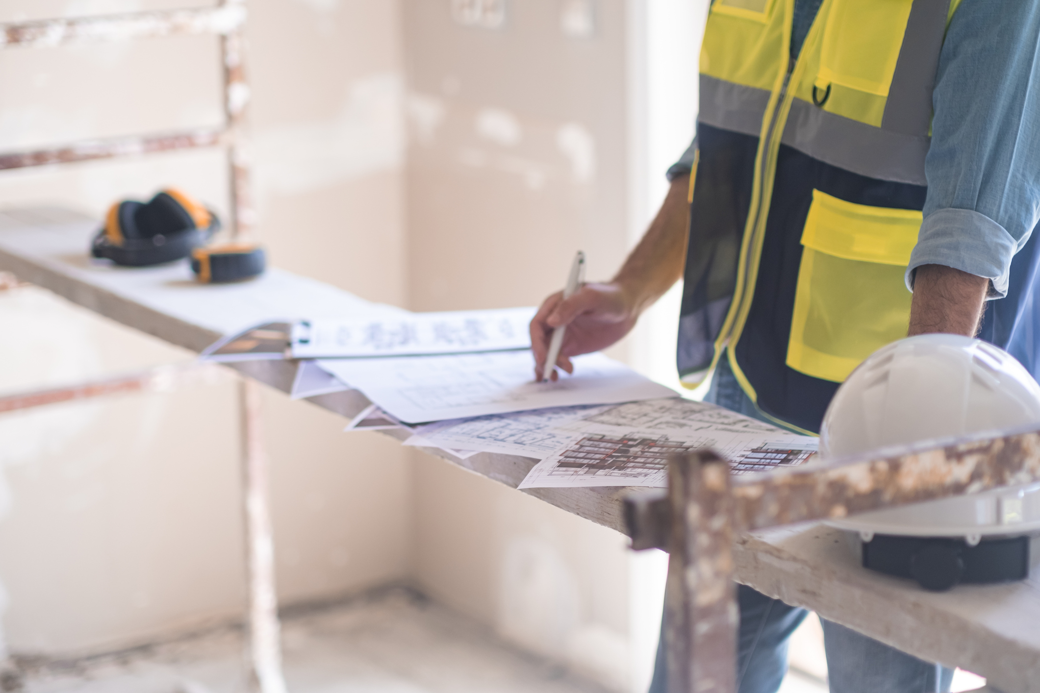 Treballador d'una obra escriu en uns plànols. 