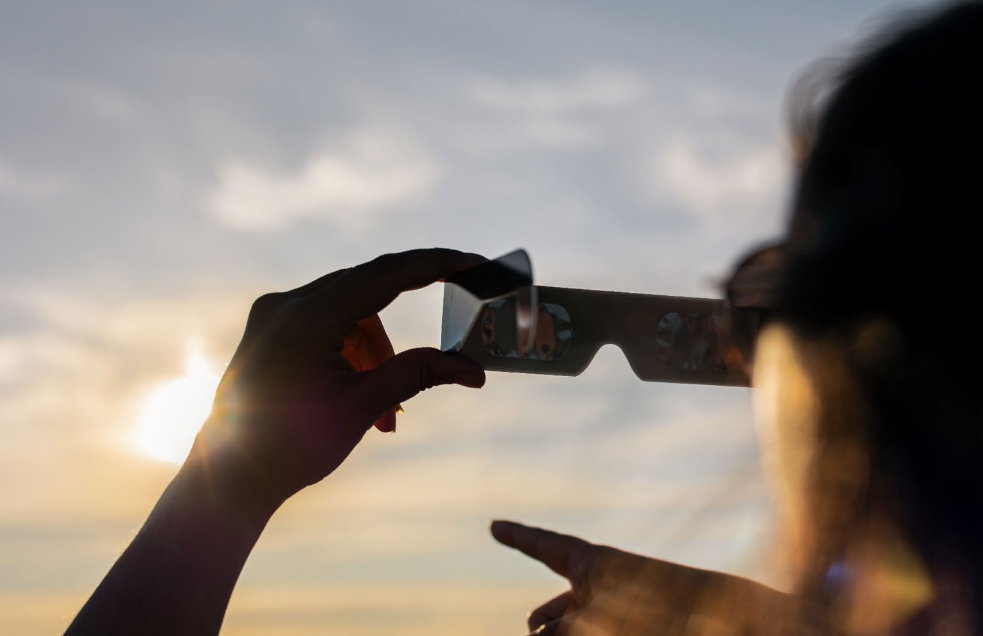 Una mujer mira el sol con unas gafas de seguridad