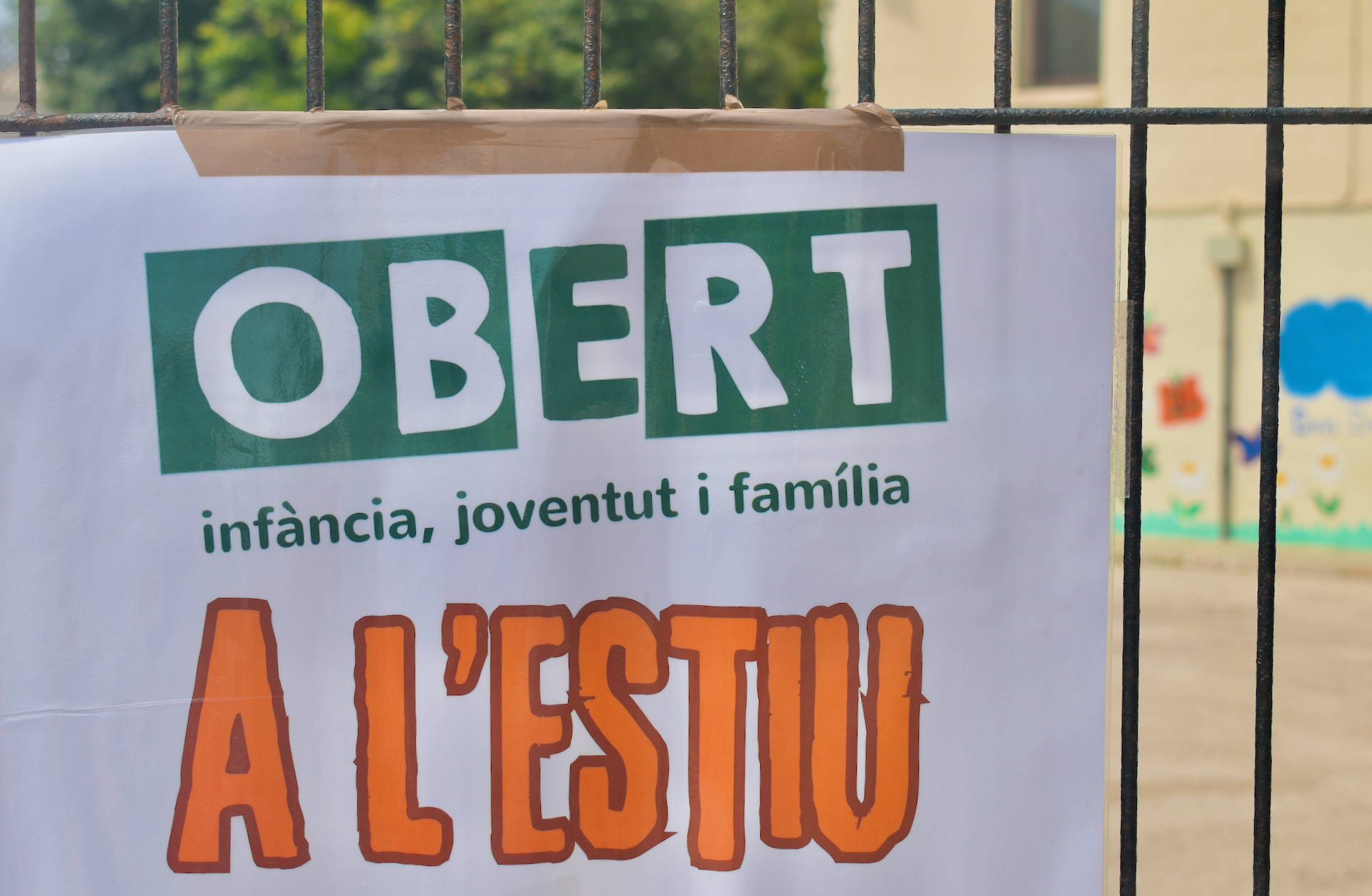 Cartell en un pati, que diu: «Obert a l'estiu. Infància, joventut i família».
